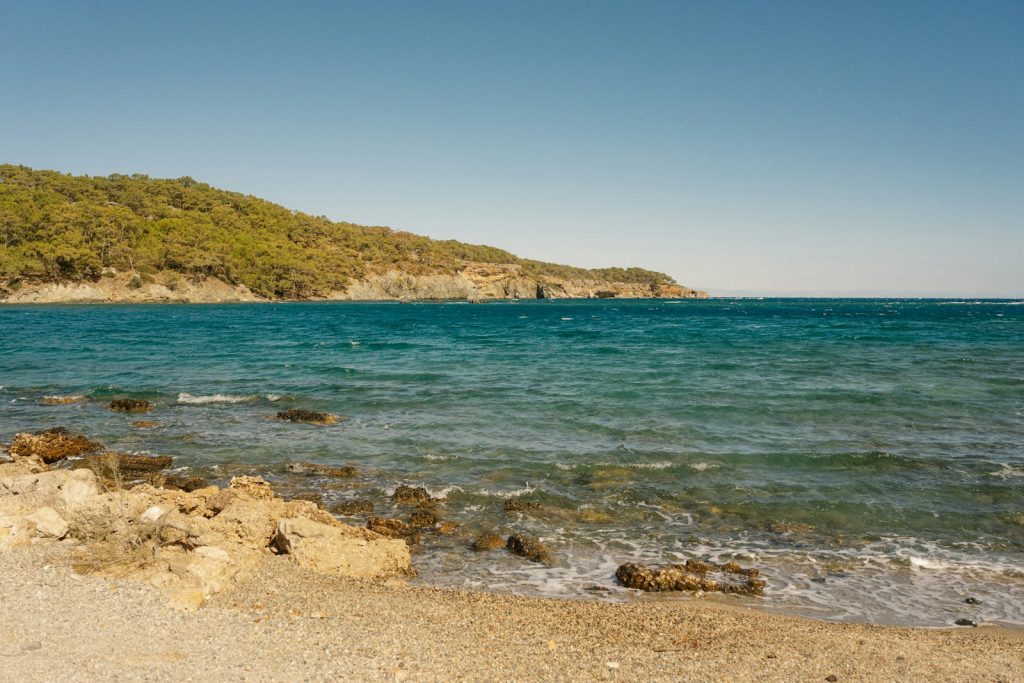 Kavicsos part és fenyves domb Phaselis ókori városánál, Kemer és Tekirova között