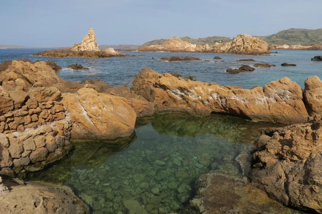 Vörös sziklák és tiszta víz a Cala Pregonda öbölben, Menorca