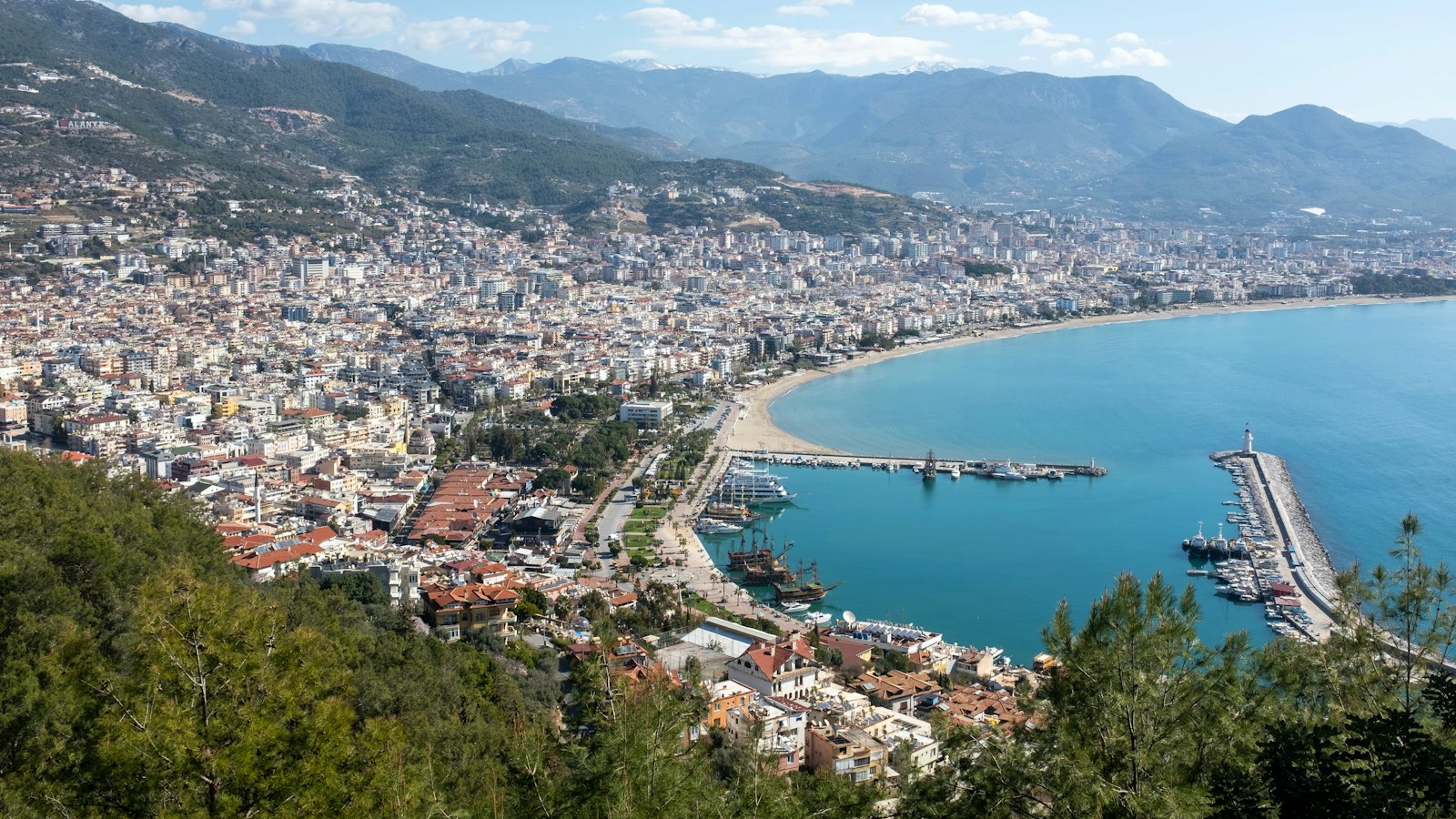 Alanya látképe a várhegyről: a Kleopátra-strand íve, a kikötő és mögötte a Taurus-hegység